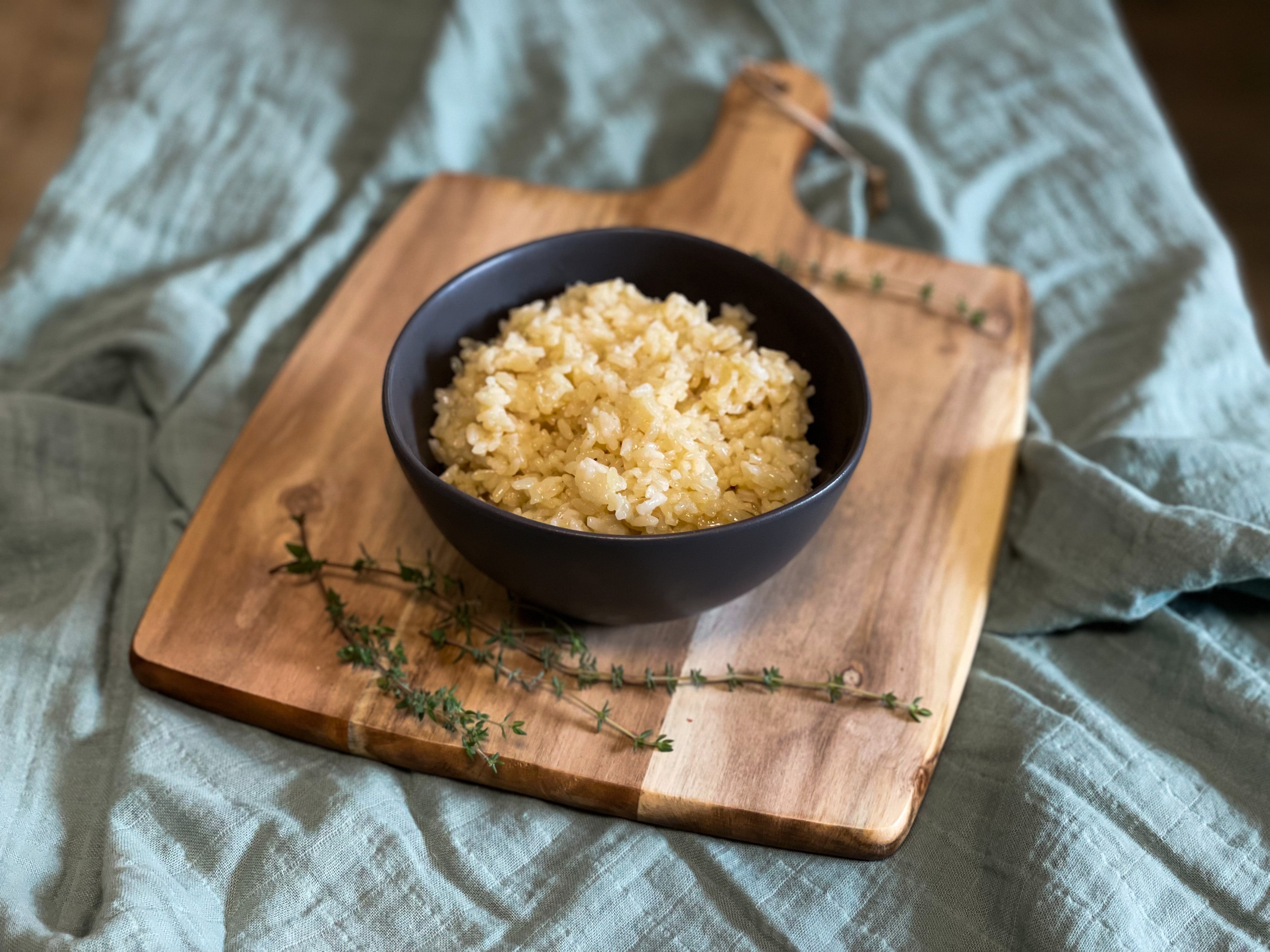 Bowl of rice sitting on cutting board.
